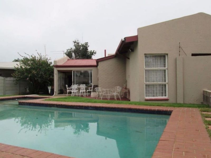 Rear view of the property featuring a swimming pool with brick coping, sliding door access to the interior, and a metal roof.