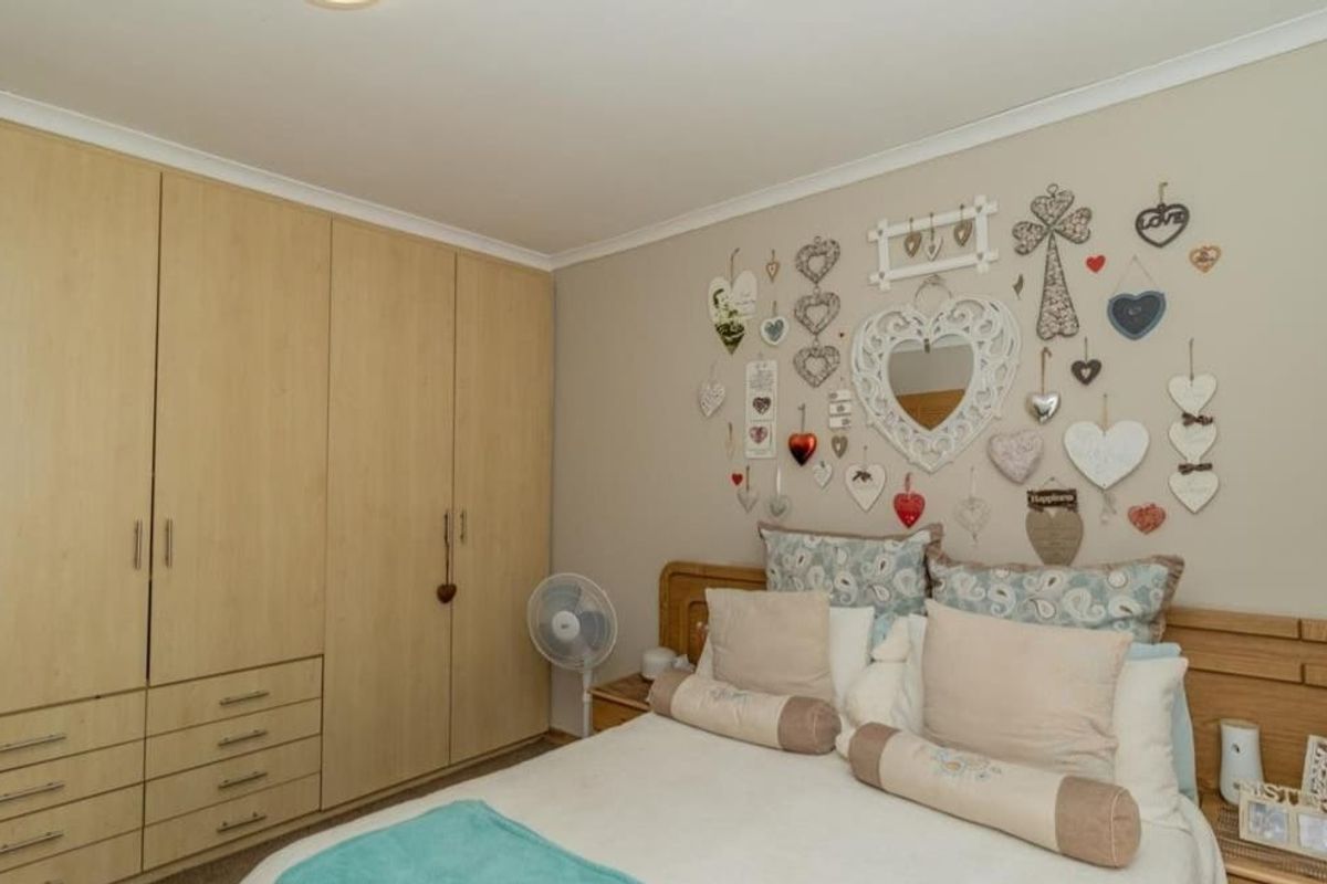 A bedroom featuring light wood-toned built-in wardrobes with integrated drawers and neutral wall finishes.