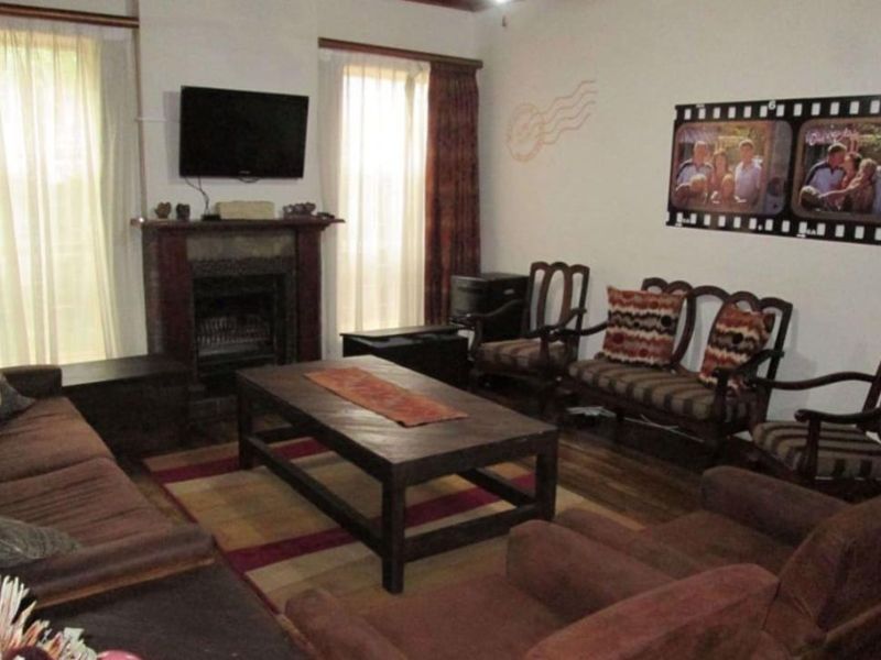 A cozy living room featuring a traditional fireplace with a mantelpiece and warm timber flooring, offering a comfortable space for relaxation.