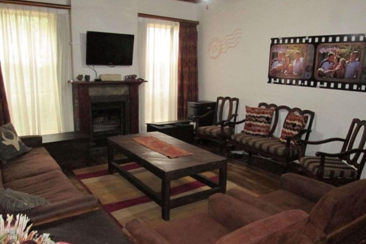 A cozy living room featuring a traditional fireplace with a mantelpiece and warm timber flooring, offering a comfortable space for relaxation.