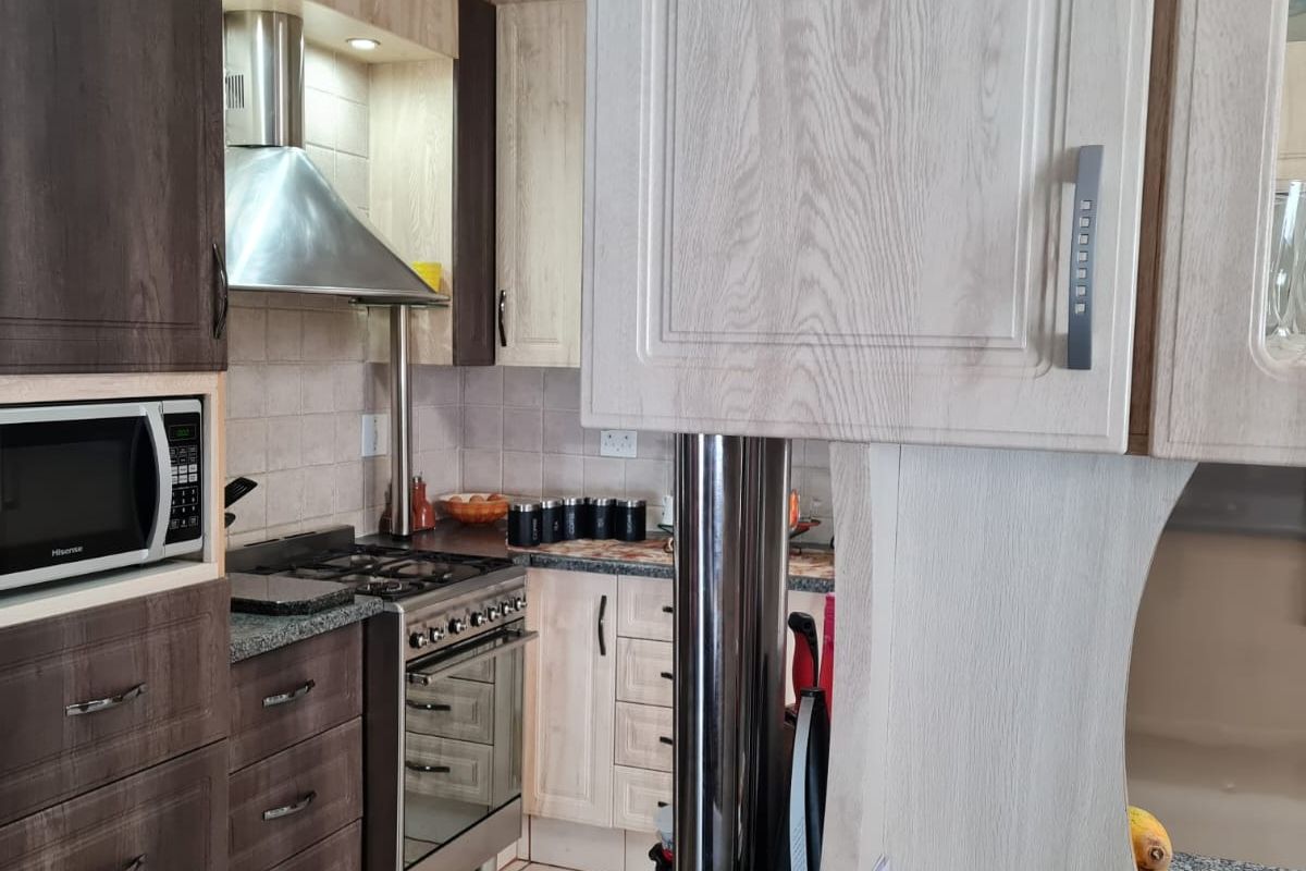 A functional kitchen featuring two-tone cabinetry, granite countertops, a gas stove with an extractor fan, and a built-in microwave.
