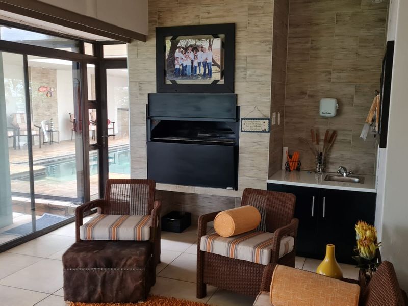 Covered patio area featuring a built-in braai, kitchenette with sink, and direct access to the pool area through sliding glass doors.