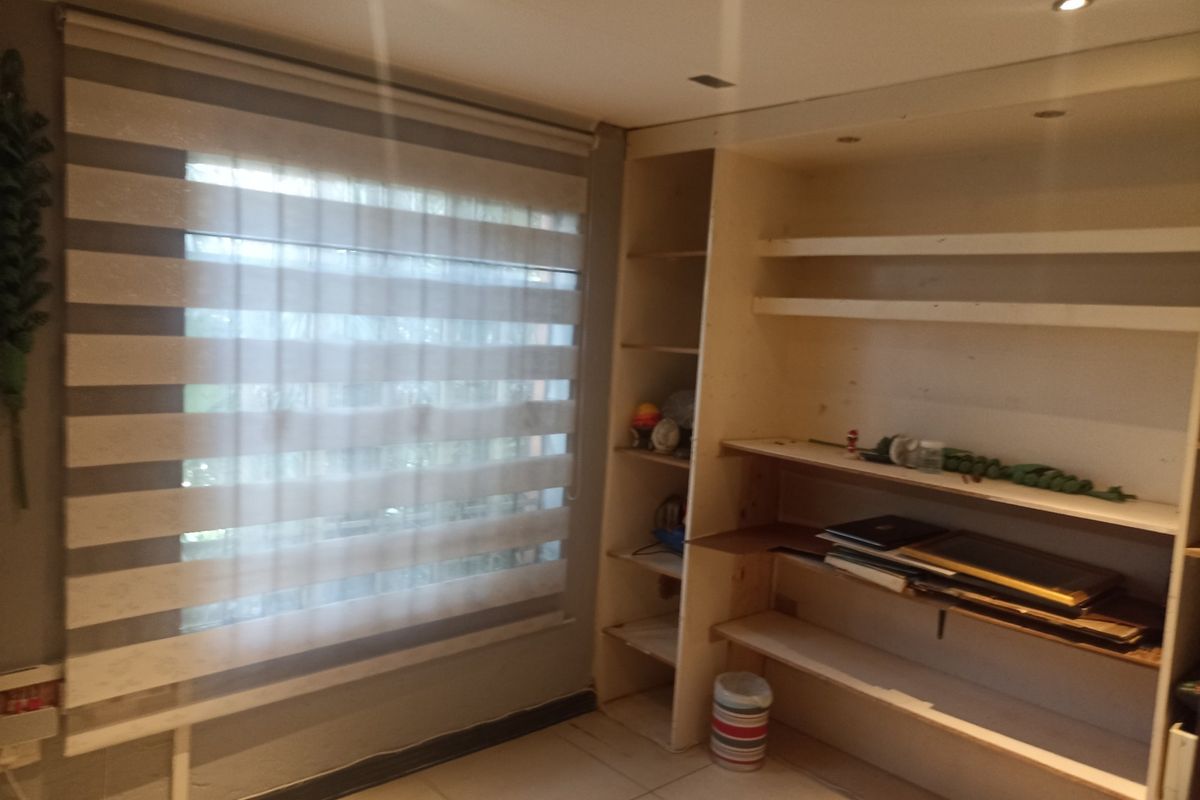 A bedroom featuring built-in shelving, tiled flooring, and recessed downlights, offering a functional space ready for personalization.