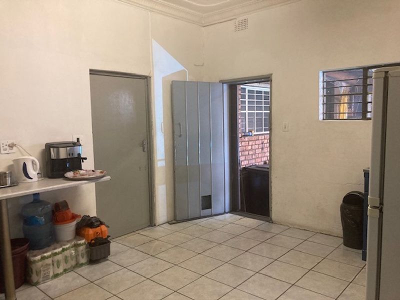 A functional kitchen area featuring tiled flooring, a security gate, and basic wall finishes, offering a blank canvas for potential renovation and modernization.