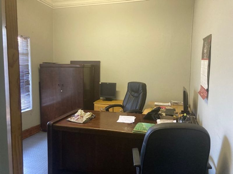 A functional office space featuring neutral walls, coving, and window blinds, suitable for a professional workspace or study.