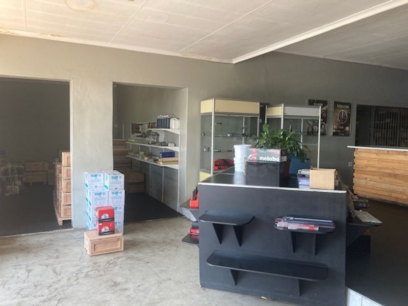Industrial utility or retail space featuring concrete flooring, built-in shelving units, and a service counter, with visible ceiling water staining.