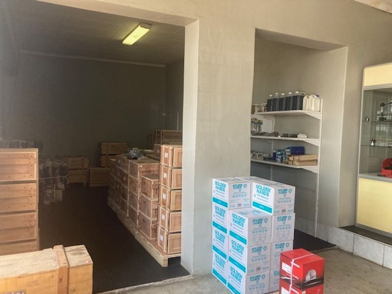 Industrial utility or storage area featuring built-in shelving units, fluorescent lighting, and durable tiled flooring, suitable for warehouse or workshop operations.