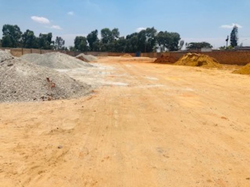 A view of a vacant commercial land plot featuring cleared ground and a perimeter boundary wall.