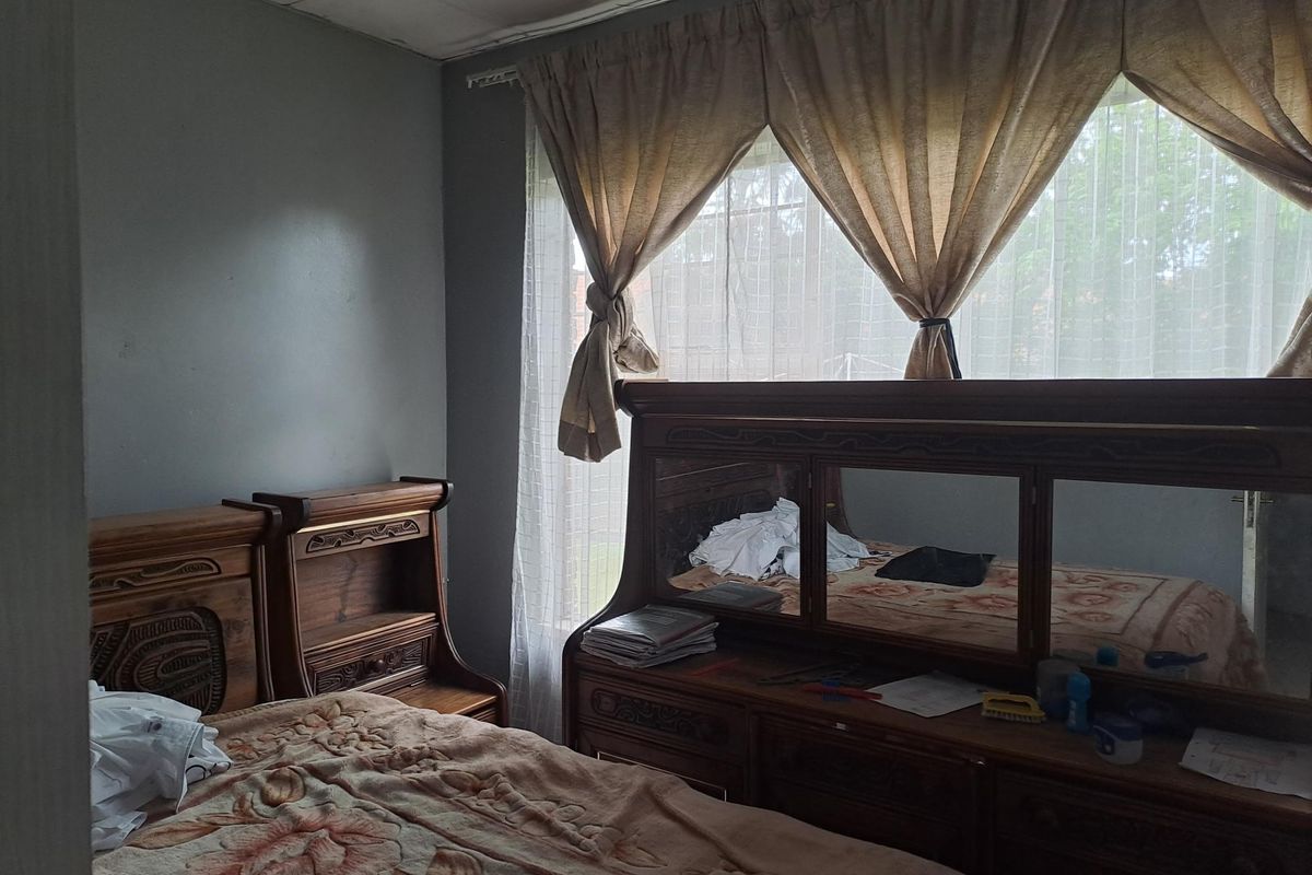 A bedroom featuring a large window with curtains, neutral wall tones, and a tiled ceiling finish.