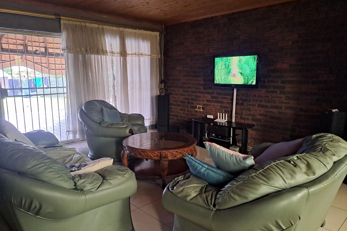 A living room featuring a rustic exposed brick feature wall, timber-clad ceiling, and large sliding glass doors providing access to the outdoor area.