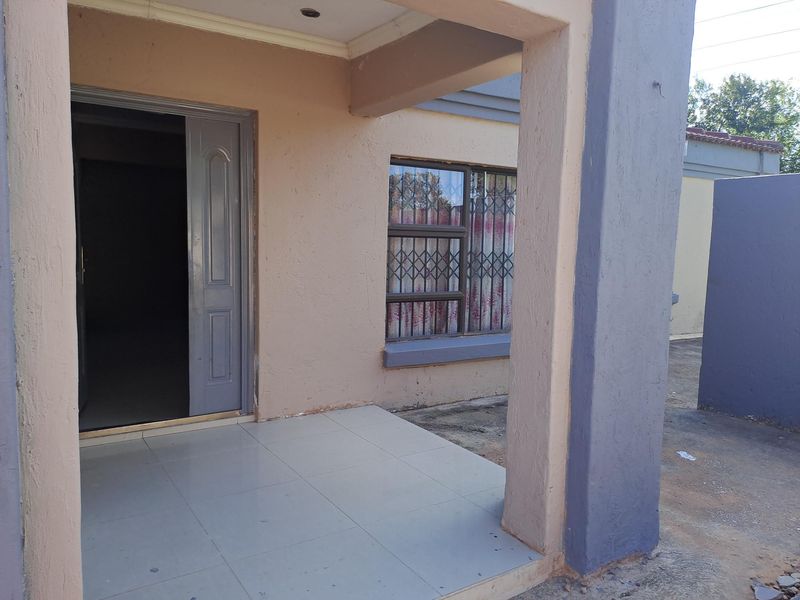 Front entrance area featuring a tiled porch, security gate, and window security bars on a painted exterior facade.