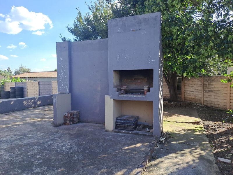 Outdoor area featuring a built-in braai structure on a concrete patio, enclosed by perimeter walls in a rear garden setting.