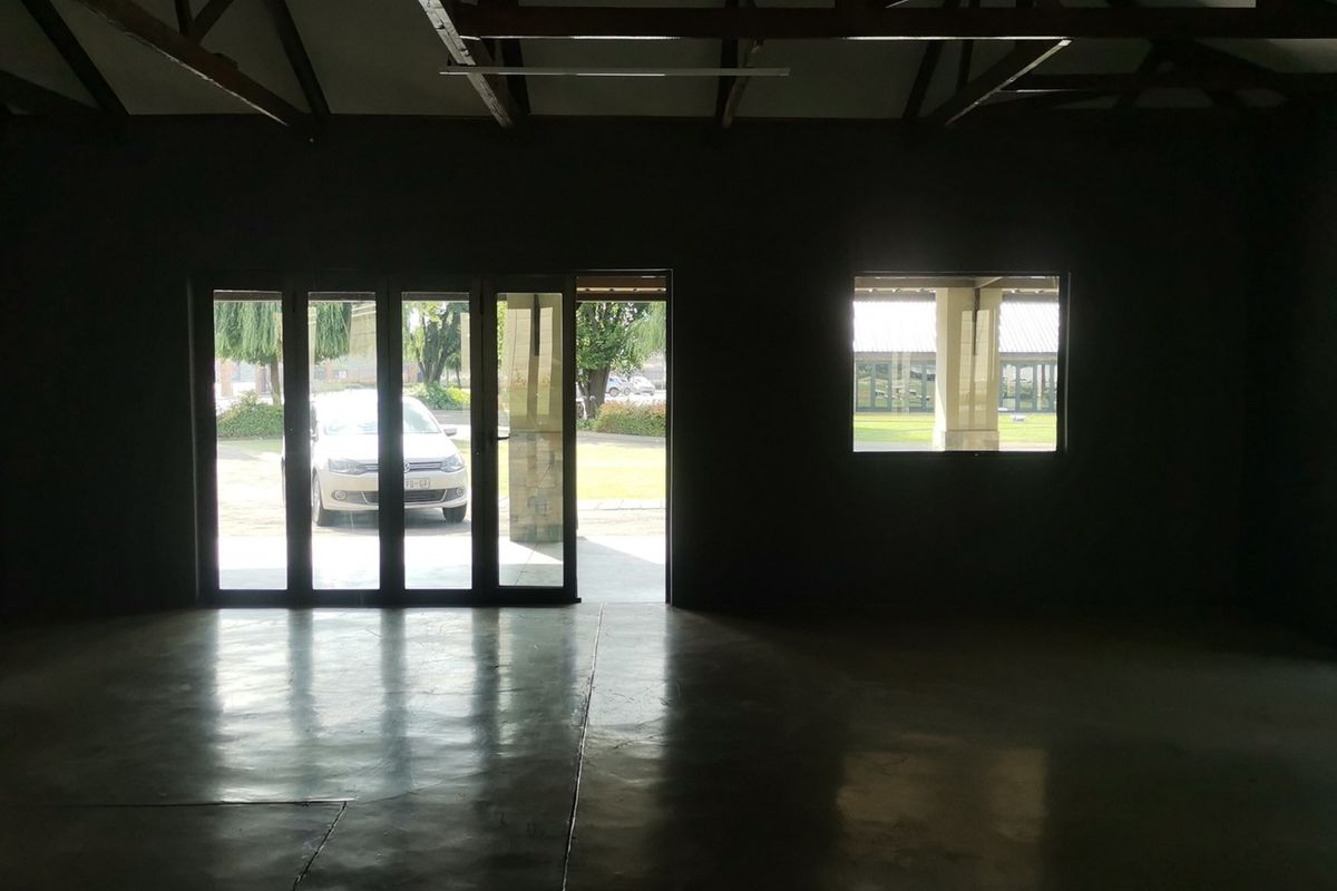 Spacious open-plan living area featuring polished concrete floors, exposed timber roof trusses, and large aluminium stacker doors providing ample natural light.