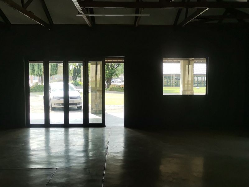 Spacious open-plan living area featuring polished concrete floors, exposed timber roof trusses, and large aluminium stacker doors providing ample natural light.