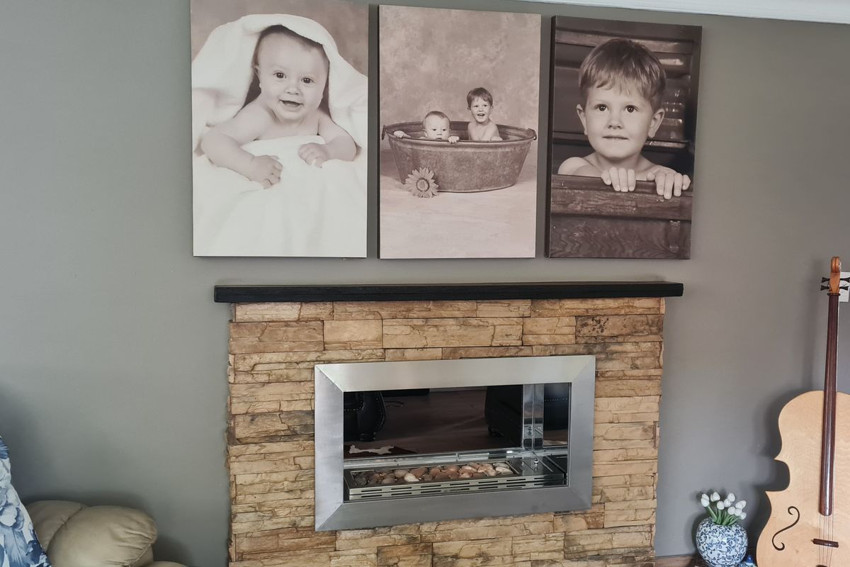 A living room feature wall showcasing a modern built-in fireplace with a stone-clad surround and a dark mantelpiece.