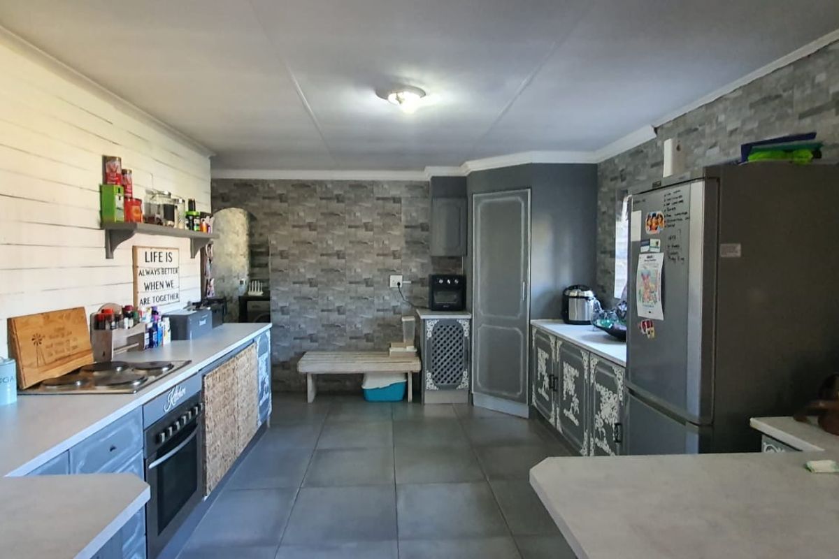 A functional kitchen featuring built-in cabinetry, a fitted oven and hob, tiled flooring, and decorative stone-effect wall cladding.