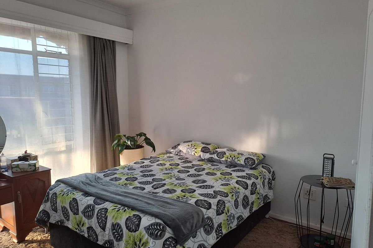A bedroom featuring a large window with curtain tracks and carpeted flooring.