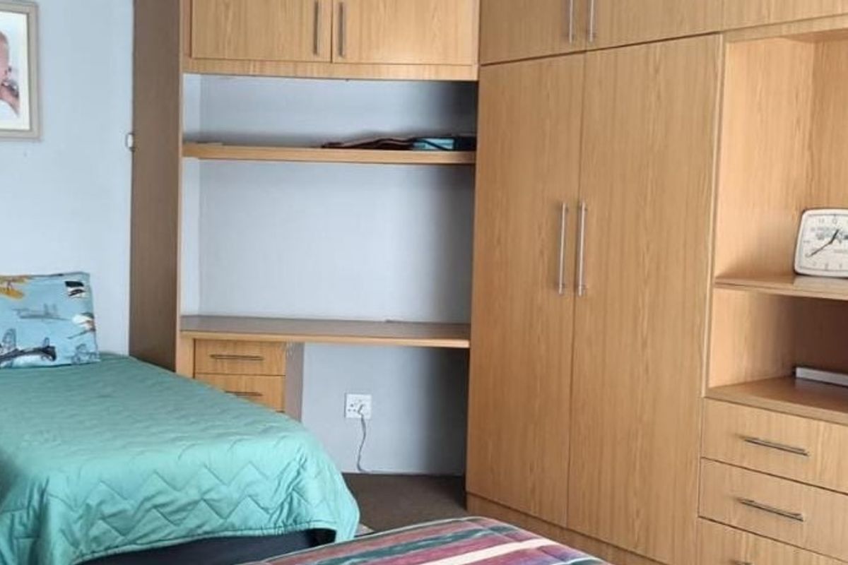 A bedroom featuring extensive built-in wooden cabinetry, including a wardrobe, integrated desk, and shelving units.