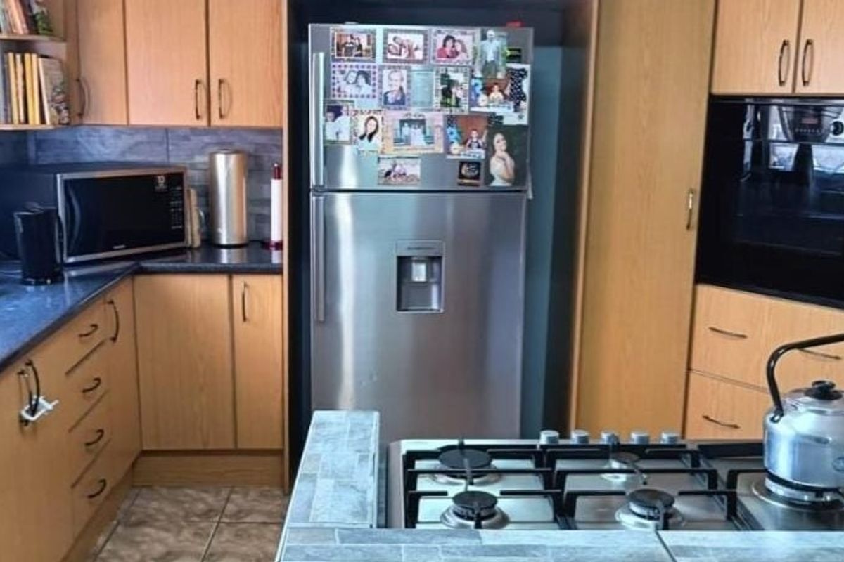 A functional kitchen featuring wood-finish cabinetry, a built-in oven, a gas hob, and dark countertops, providing a practical workspace for daily cooking.
