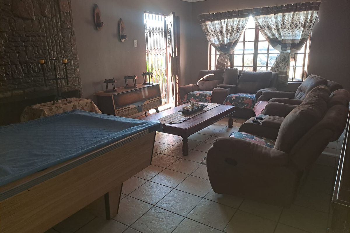 Spacious living room featuring a prominent stone-clad fireplace, tiled flooring, and direct access to the exterior through a security gate.