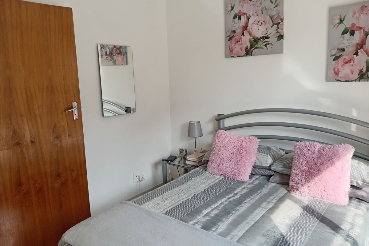 A bedroom featuring a wooden door and neutral wall finishes, providing a functional and comfortable sleeping space.