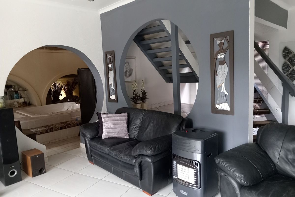 Living area featuring distinctive circular archways, tiled flooring, and an open staircase leading to the upper level.