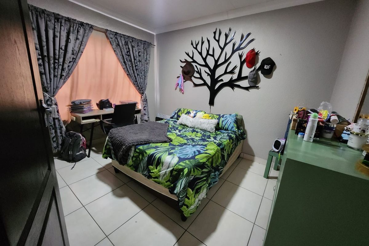 A functional bedroom featuring tiled flooring, neutral wall paint, and a window with curtain treatments.