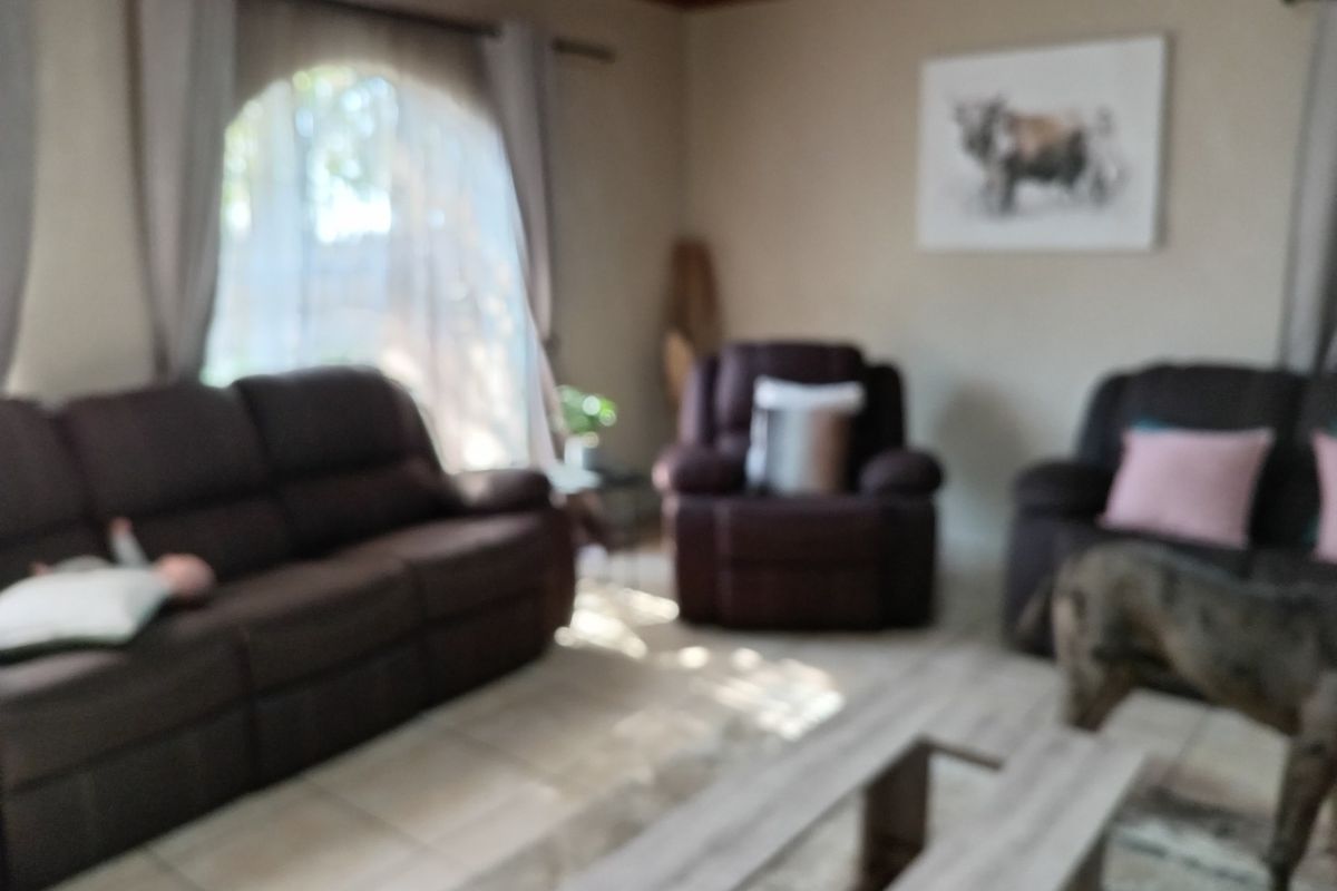 A living room featuring tiled flooring and a large arched window, providing a comfortable and functional space for relaxation.