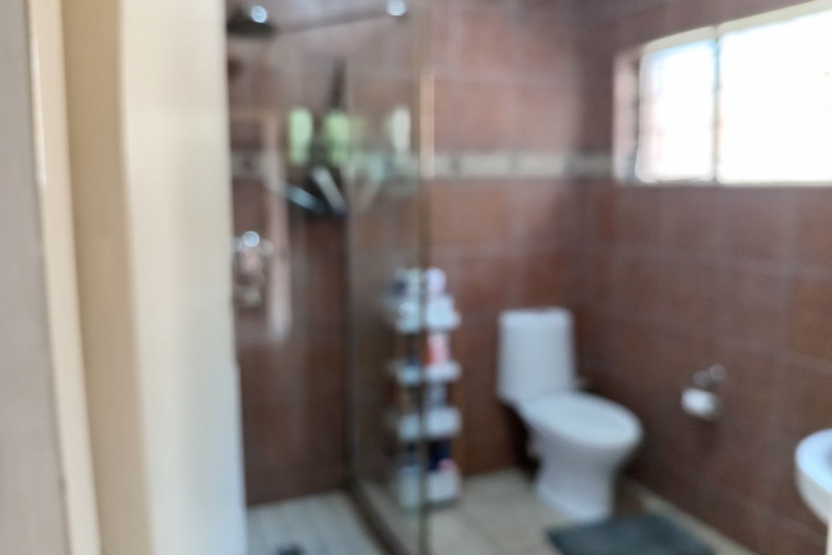 A functional bathroom featuring a glass-enclosed shower, a standard toilet, and tiled wall finishes.