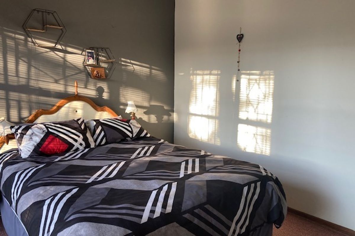 A bedroom featuring a neutral color palette with a dark accent wall and carpeted flooring.