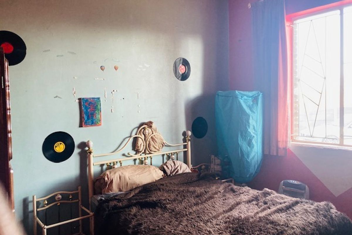 A bedroom featuring a window with security bars and painted walls.