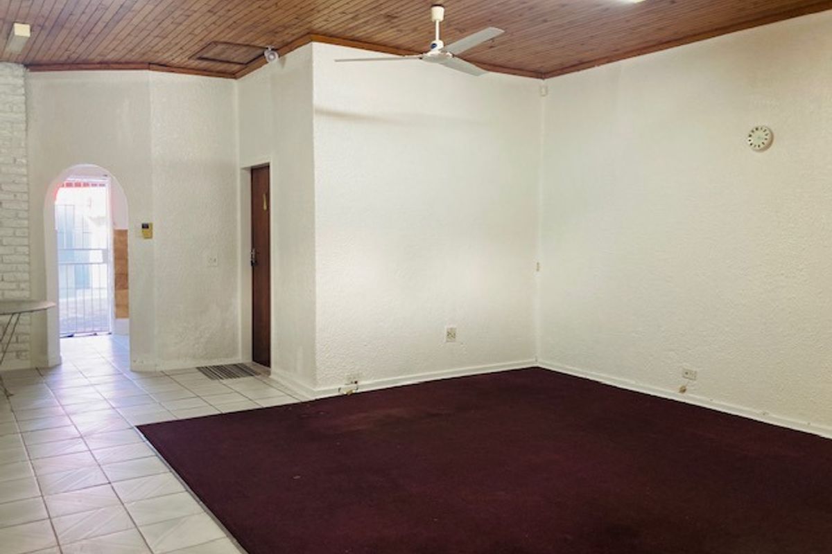 Spacious living area featuring a timber-clad ceiling, ceiling fan, and a combination of tiled and carpeted flooring with an arched entryway.