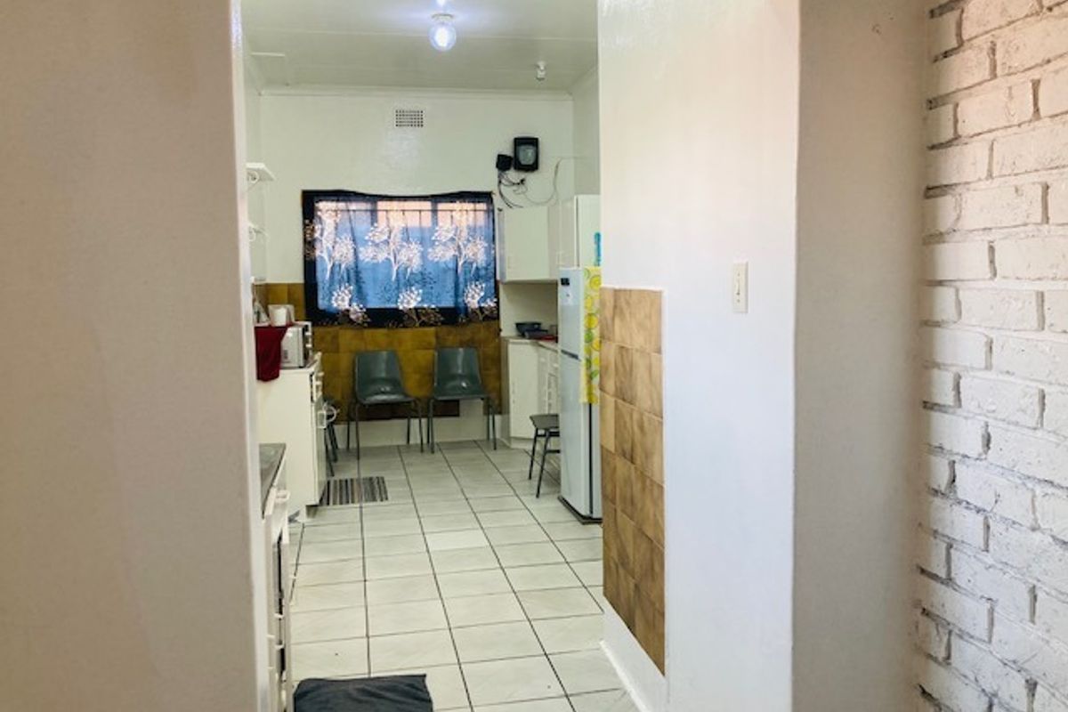 A functional kitchen space featuring tiled flooring, built-in cabinetry, and an exposed brick wall, offering potential for modernization and aesthetic updates.