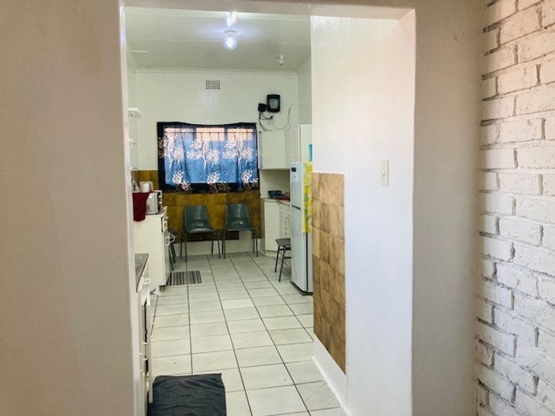A functional kitchen space featuring tiled flooring, built-in cabinetry, and an exposed brick wall, offering potential for modernization and aesthetic updates.