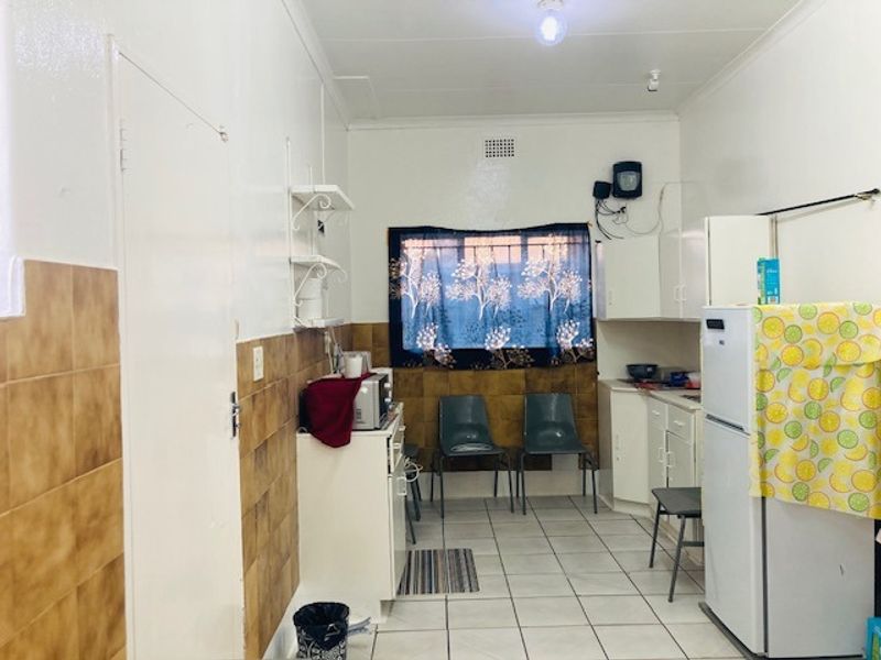 A functional kitchen space featuring tiled flooring, a tiled splashback, and built-in cabinetry, offering a dated aesthetic ready for modernization.