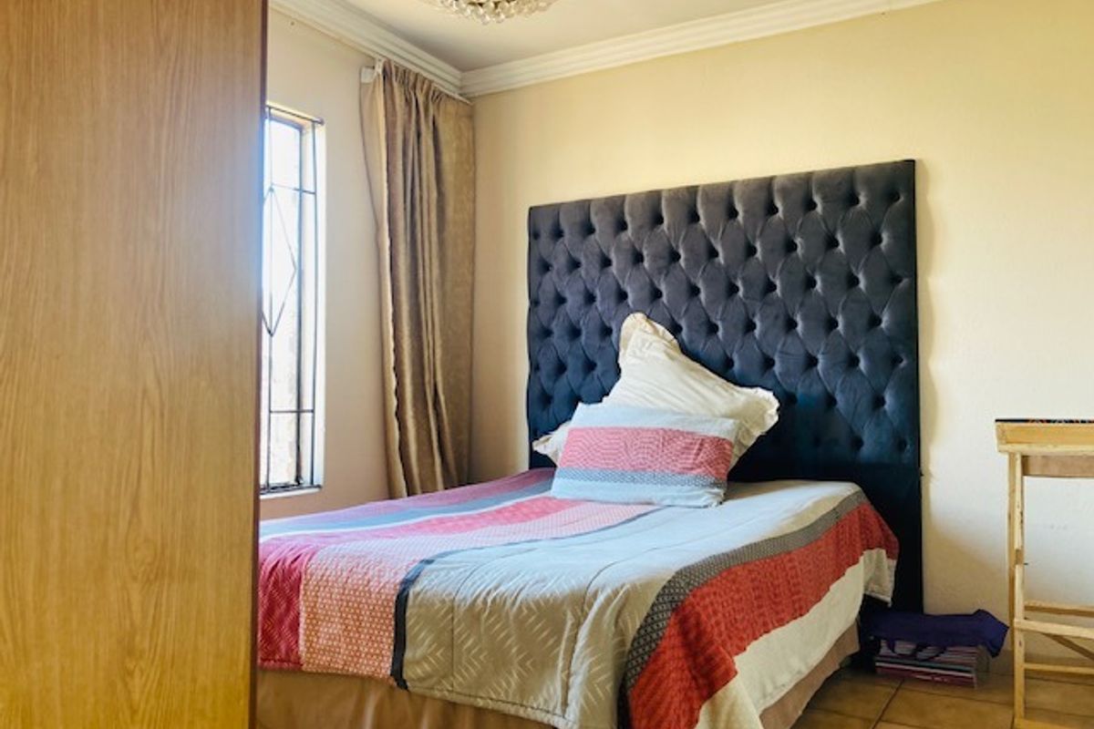 A bedroom featuring tiled flooring, a window with security bars, and crown molding.