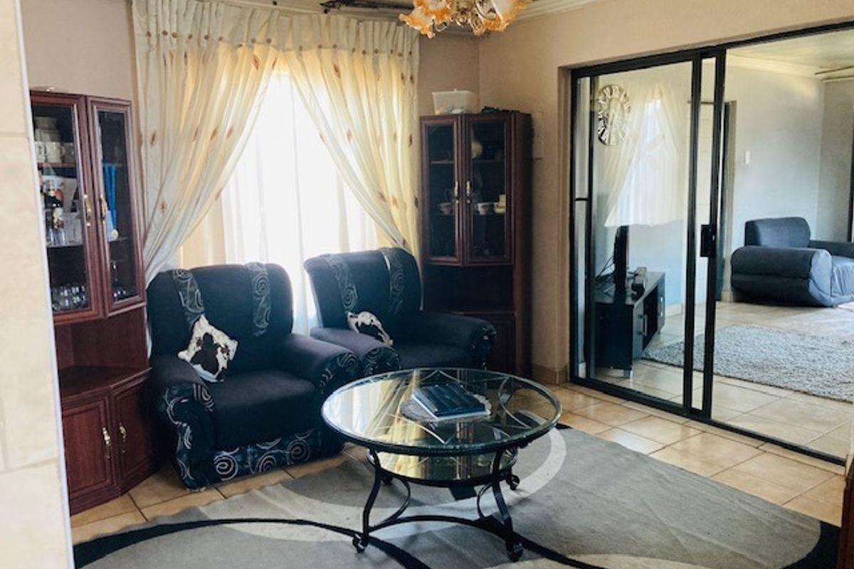 A living room featuring tiled flooring, sliding glass doors leading to an adjacent space, and a central ceiling light fixture.
