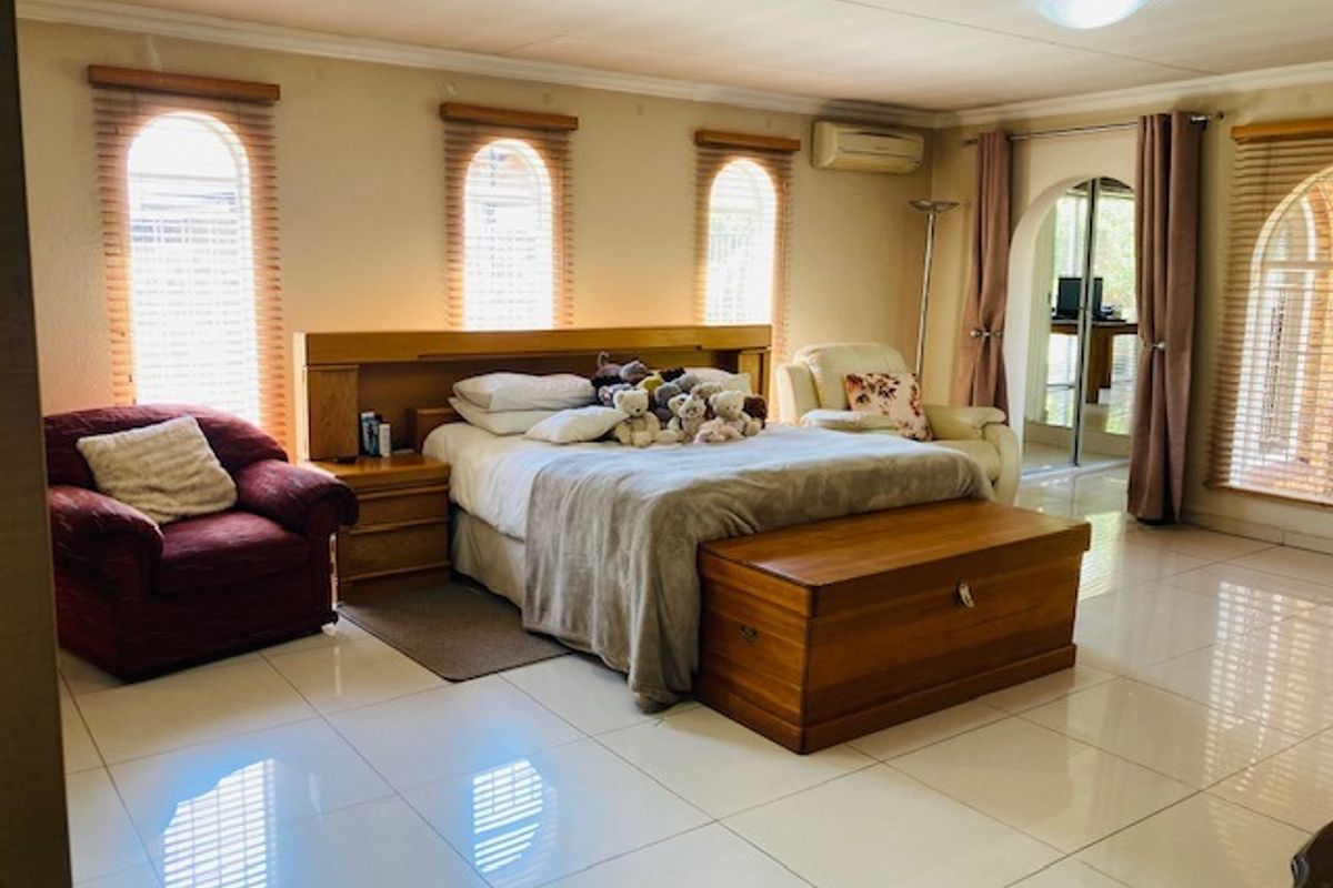 Spacious bedroom featuring large arched windows, polished tile flooring, and a built-in headboard with integrated bedside tables.