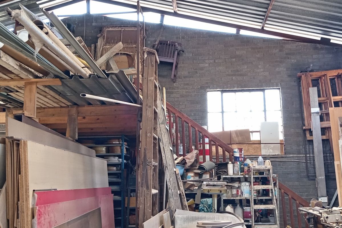 Industrial utility space featuring exposed brick walls, a corrugated metal roof, and a mezzanine level accessed by a timber staircase.