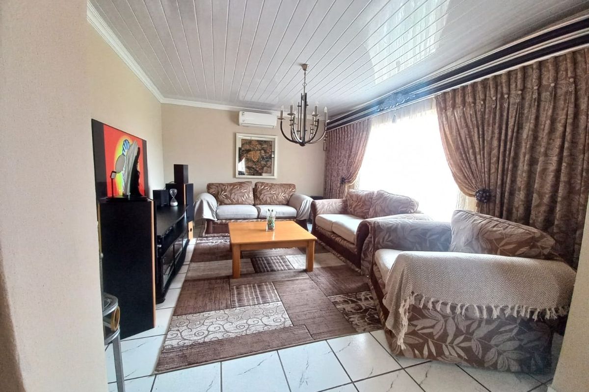 A spacious living room featuring tiled flooring, a tongue and groove ceiling, and a wall-mounted air conditioning unit.