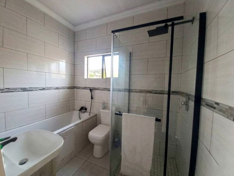 Modern bathroom featuring a glass-enclosed shower, separate bathtub, toilet, and basin with neutral wall and floor tiling.
