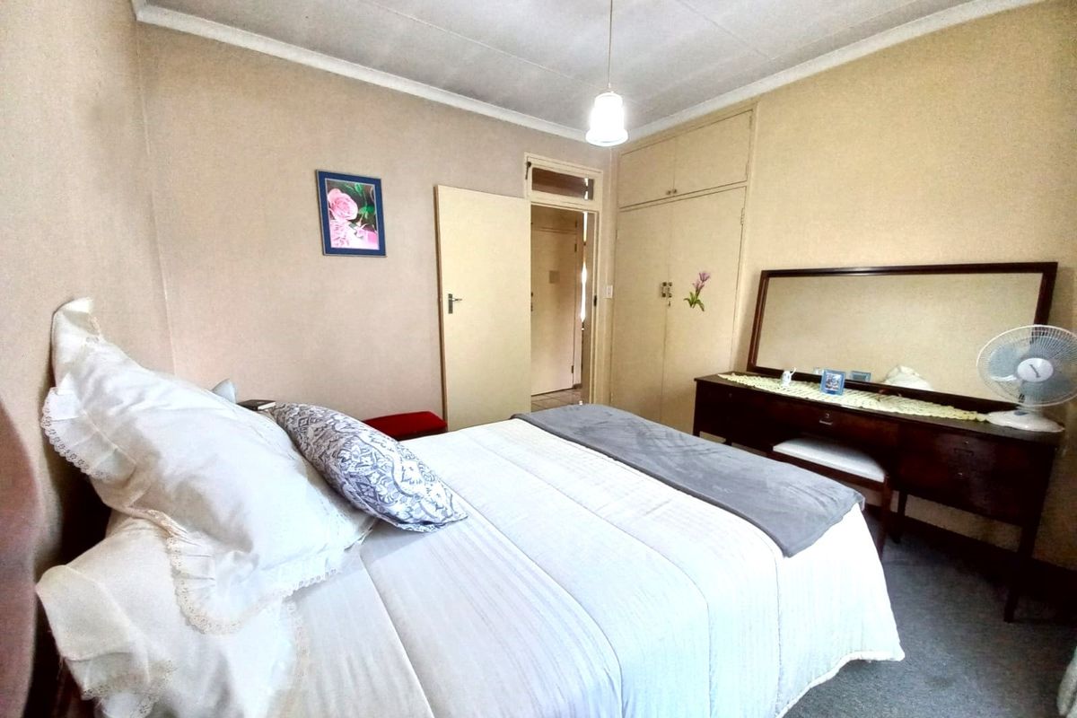 A functional bedroom featuring built-in cupboards and coved ceiling detailing, offering a neutral canvas for potential modern updates.