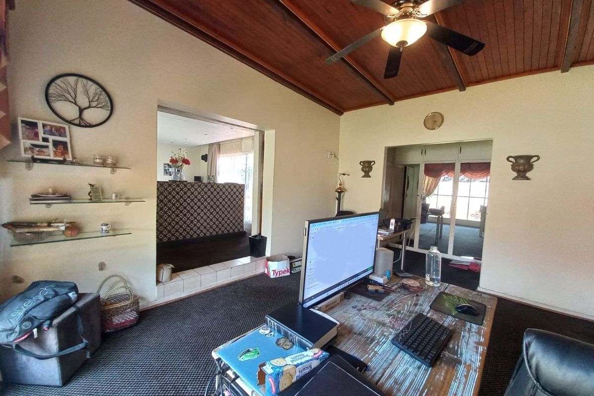 Spacious living area featuring a timber-clad ceiling with a central fan, built-in shelving, and an open-plan layout connecting to adjacent rooms.