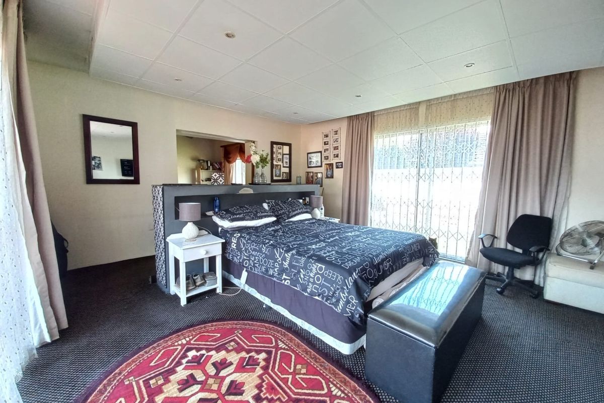 Spacious bedroom featuring a drop ceiling with recessed lighting and direct access to the exterior through a sliding glass door with security gate.