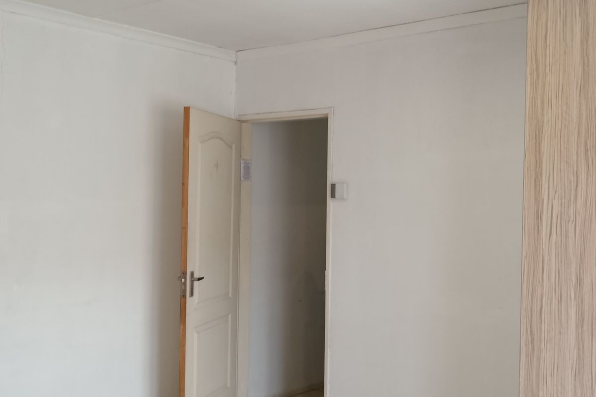 A bedroom interior featuring built-in wooden cabinetry and direct access to an adjoining bathroom.