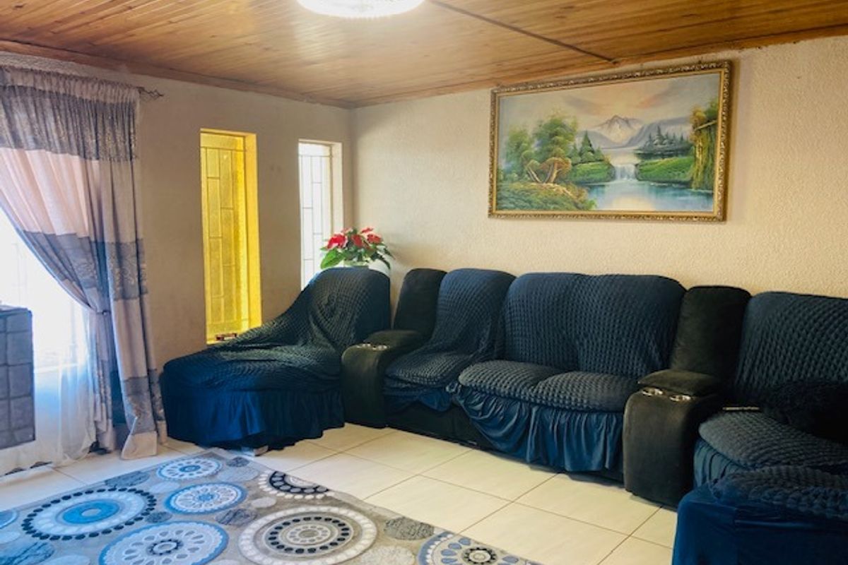 A living room featuring a timber-clad ceiling, tiled flooring, and narrow vertical windows with security bars.