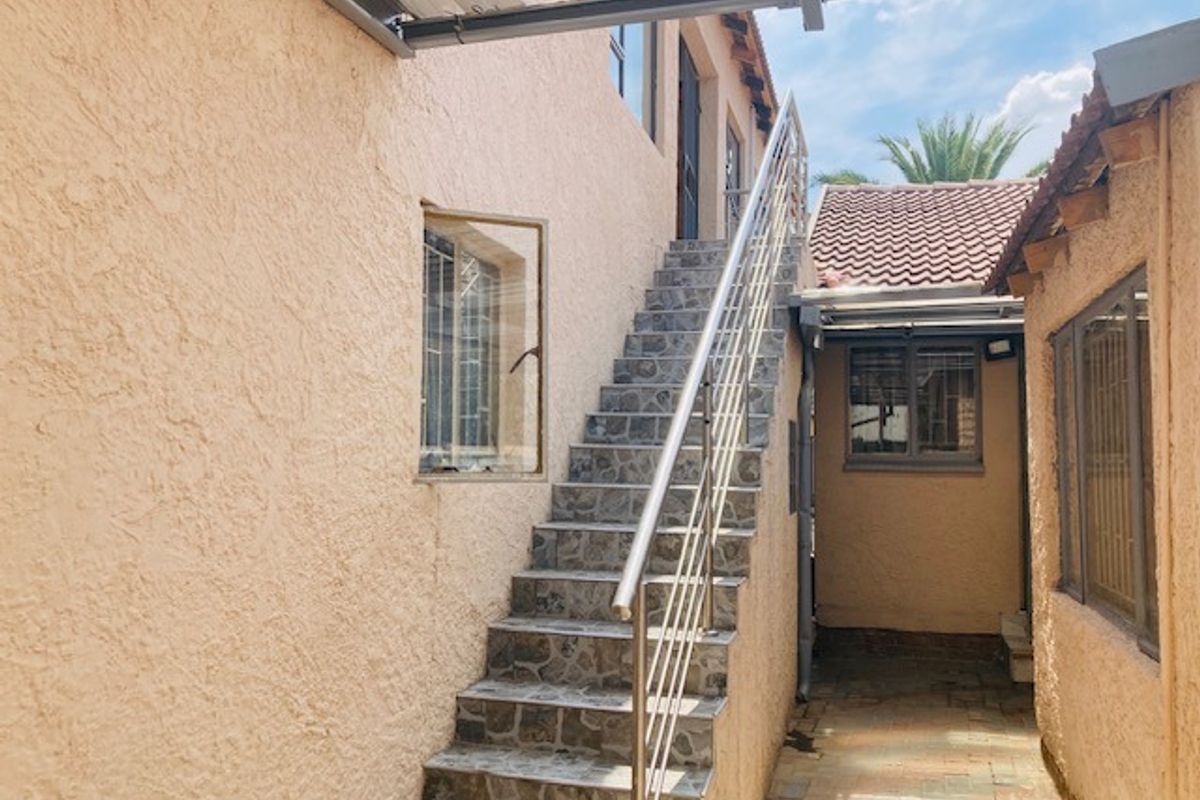Exterior view featuring an external staircase with metal railings leading to an upper level, set between two textured residential building structures.