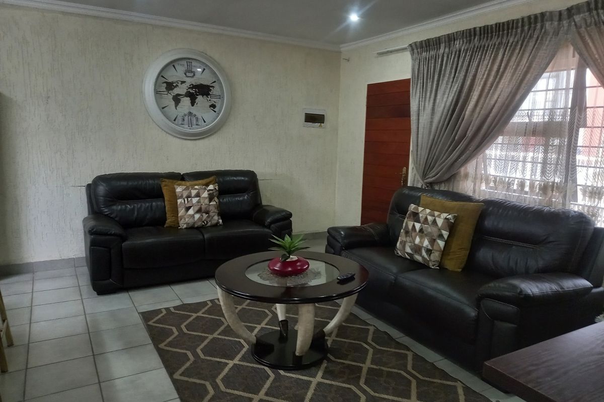 A comfortable living room featuring tiled flooring, recessed ceiling lighting, and a large window with curtain treatments.