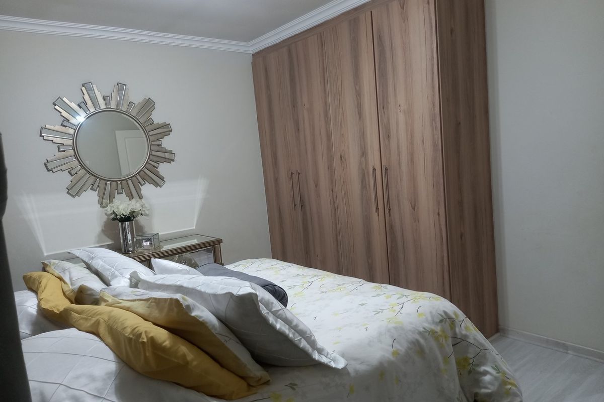 A well-maintained bedroom featuring built-in wooden wardrobes and crown molding, providing ample storage and a clean, neutral aesthetic.