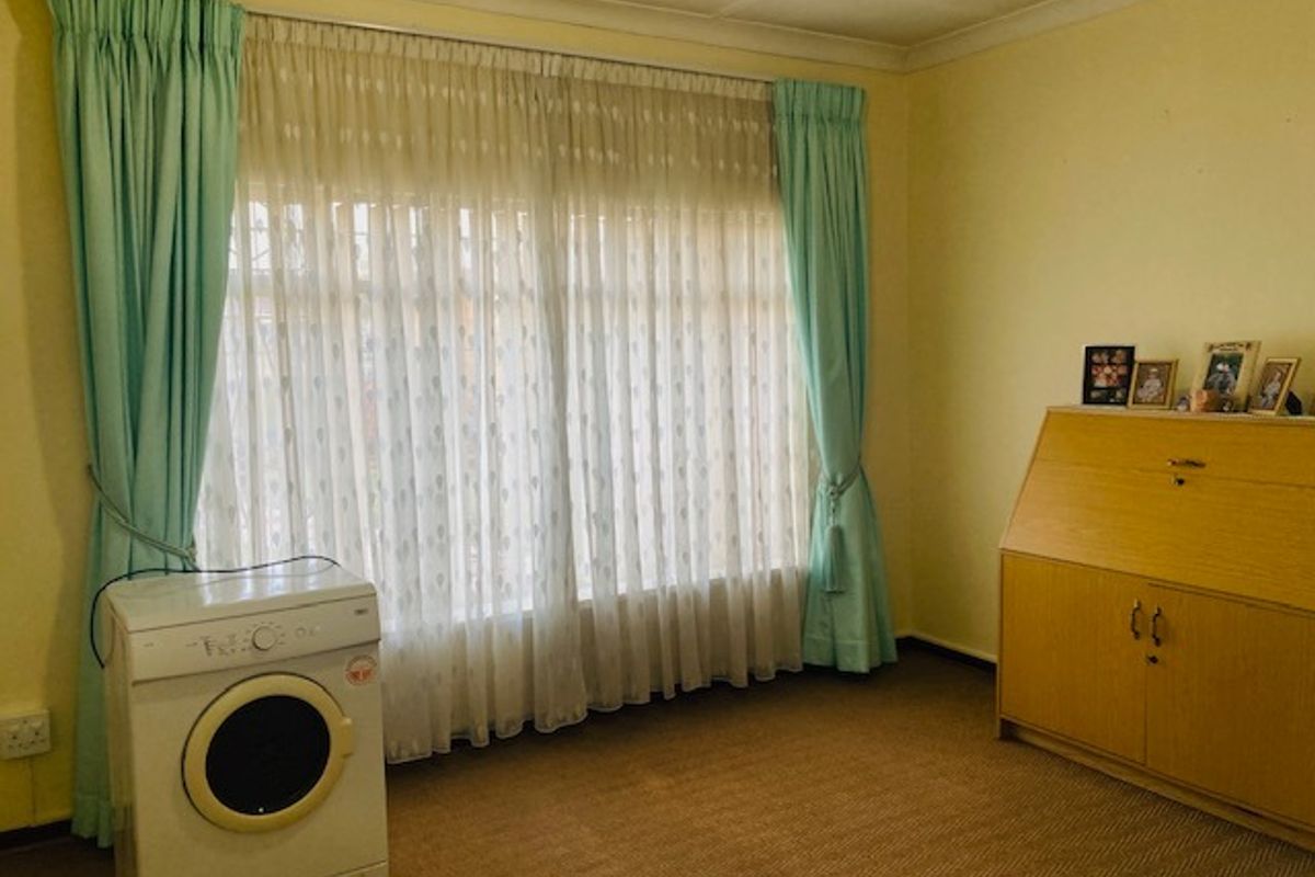 A bedroom featuring large windows with curtains, carpeted flooring, and neutral wall finishes.
